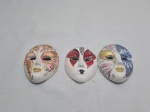 Lote de 3 máscaras decorativas para pendurar em porcelana pintada. Medindo a maior 9cm x 6,5cm.