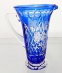 CRISTAL DOUBLÉ - Grande jarra em cristal doublé lapidada a mão com elementos geométricos, palmas e flores. Mede 24 cm de altura por 22 cm da alça ao bico.