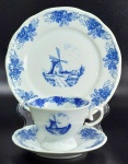 PORCELANA SCHMIDT - Trio para chá e bolo em porcelana Schmidt decorados por cenário holandês blue and white emoldurado por faixa floral nas bordas. Medindo 7 X 9,5 cm a xícara, 14,5 cm de diâmetro o pires e 19,5 cm de diâmetro o prato para sobremesa. 