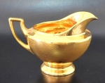 ROYAL - Cremeira em porcelana Royal com farta aplicação de ouro. Decorada com flores em relevo na parte externa. Minimas marcas do tempo. Medidas 9cm de altura por 14cm de alça ao bico.
