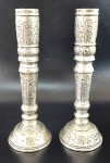 CASTIÇAIS - Par de castiçais em metal espessurado a prata com rico cinzelamento em formato fitomorfico em baixo relevo. Medindo 21cm de altura e 7,5cm de diametro na base