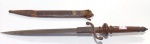 7 - "PLUG BAYONET", COMPRIMENTO TOTAL 39,5 CM, LÂMINA BIFILAR DE 24,5 CM X 2 CM, CABO EM MADEIRA, GUARDA EM FERRO BATIDO, BAINHA COM PONTEIRA