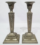Elegante par e castiçais trabalhados em metal prateado de excelente fundição, adornados por ricos trabalhos, principal motivo dito laçarote. Medem 24,5 x 10 x 10 cm. Bom estado de conservação.