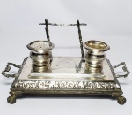 Antigo e elegante tinteiro executado em metal espessurado á prata de ótima qualidade e fundição, rico trabalho de volutas nas bordas, sustentado por quatro pés firmes. Mede 13 x 30 x 16 cm. Bom estado de conservação.