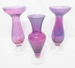 Elegante lote composto por três grandes vasos executados em vidro artístico facetado em tonalidades violeta e translúcida. Maior mede 34,5 cm de altura x 15 cm de diâmetro. Bom estado de conservação.