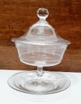 SAINT LOUIS - FRANÇA - Antiga e belíssima compoteira finamente executada em cristal de tonalidade translúcida de excepcional qualidade e manufatura francesa, adornada por rico trabalho clássico da marca, pega da tampa ricamente lapidada, apoiada por lindo presentoir de mesmo feitio. Mede 22 cm de altura x 18 cm de diâmetro do presentoir. Impecável estado de conservação. França meados do Século XX.