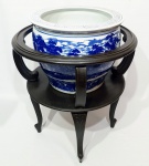 IMPONENTE VASO CACHEPO EM PORCELANA FLOW BLUE FINAMENTE DECORADA COM BELÍSSIMA CENA CAMPESTRE. ACOMPANHA BASE EM MADEIRA ELEVADA SOBRE ELEGANTES PÉS RECURVOS. CHINA MEADOS DO SÉCULO XX. EXCELENTE ESTADO DE CONSERVAÇÃO. Cachepo mede :28 cm de altura x 35 cm de diâmetro. Base de madeira: 50 x 50 cm.