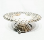 Elegante fruteira centro de mesa executada em metal espessurado á prata de ótima fundição, rico trabalho nas bordas e base, segurada por 3 pés firmes com detalhes de volutas. Mede 13,5 cm de altura x 36 cm de diâmetro. Bom estado de conservação.