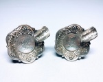 Clássico par de cinzeiros em prata de lei teor 833, feitio de excepcional ourivesaria com rico trabalho e moedas de 1.000 e 500 Réis. Brasil inicio do séc XX. medem aprox  2,5 x 5,0 cm, cada. Excelente estado de conservação. Peso bruto 73.9 gramas.
