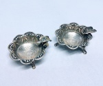 Clássico par de cinzeiros em prata de lei teor 900, feitio de excepcional ourivesaria com rico trabalho e moedas do Império de 1.000 Réis datadas de 1856 e 1865. Brasil inicio do séc XX. medem aprox  2,5 x 5,0 cm, cada. Excelente estado de conservação. Peso bruto 60 gramas.