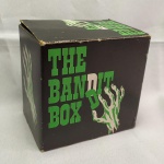 BRINQUEDO ANTIGO - COFRINHO denominado THE BANDIT BOX, na caixa original. Funcionando com duas pilhas tipo AA. Ao se colocar uma moeda no dispositivo próprio, uma mão sai da caixa e apanha a moeda. Fabricado no Japão em 1972