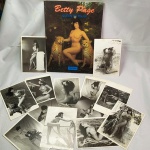 Lote com 14 (quatorze) Cartões POSTAIS e LIVRO CATÁLOGO da TASCHEN da famosa PIN-UP BETTIE PAGE (Betty Page Queen of Pin-Up). Os postais apresentam marcas do tempo. Bettie Page foi uma modelo norte-americana que se tornou famosa na década de 1950 por fotos de temática pin-up e fetichista. Ela é frequentemente chamada de `Rainha das Pin-ups` e seu visual, cuja marca registrada eram os cabelos pretos lustrosos e uma franja, influenciaram dezenas de artistas. Fonte Wikipédia. No final da década de 1970, Bettie foi diagnosticada com esquizofrenia e acabou sendo presa por causa de um surto psicótico, permanecendo por 10 anos na cadeia. Durante essa época, ninguém sabia do paradeiro da Rainha das Pin-ups dos anos 1950.