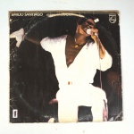 Vinil  Emílio Santiago  Guerreiro Coração (gravado ao vivo). Produto Original. Gravadora PHILIPS. Fabricado e distribuído por Polygram Discos Ltda. 1980. Capa (escurecida, com pontos de oxidação, etiqueta colada, assinatura/rasuras e com desgastes do material)/contracapa (com pontos de oxidação, escurecida e danificada nas pontas) em regular estado de conservação, danificada nas bordas colada com fita adesiva, manchas/pontos de oxidação, marcação do disco, com sinais de uso, manuseio e desgastes. Não contém plástico de proteção do disco. Disco com riscos, mesmo que superficiais podem ocasionar algum nível de ruído na audição. Não contém encarte. Lado A  7 faixas; Lado B   7 faixas.