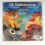 Vinil  Os saltimbancos  Luiz Enriquez/Sérgio Bardotti/Chico Buarque.  Produto Original. Gravadora PHILIPS. 1977. Fabricado e distribuído por Companhia Brasileira de Discos. Capa (desgastes do material faltando algumas partes, sinais de umidade, escurecida e com rasuras)/contracapa (com desgastes do material, pontos de oxidação e escurecida) em regular estado de conservação, danificada nas bordas colada com fita adesiva, manchas/pontos de oxidação, marcação do disco, com sinais de uso, manuseio e desgastes. Não contém plástico de proteção do disco. Disco com riscos, mesmo que superficiais podem ocasionar algum nível de ruído na audição. Não contém encarte. Selo fonográfico com assinatura. Lado A  6 faixas; Lado B   7 faixas.