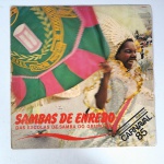 Vinil  Sambas de enredo  das escolas de samba do grupo 1ª  Gravações originais  Carnaval 85.  Produto Original. Gravadora Tope Tape. 1984. Fabricado e distribuído por Tope Tape Musica Ltda. Capa (com desgastes do material faltando algumas partes, escurecida e pontos de oxidação)/contracapa (desgastes do material, escurecida e pontos de oxidação) em regular estado de conservação, danificada nas bordas colada com fita adesiva transparente, manchas/pontos de oxidação, marcação do disco, com sinais de uso, manuseio e desgastes. Contém plástico de proteção do disco, porém o mesmo está danificado. Disco com riscos, mesmo que superficiais podem ocasionar algum nível de ruído na audição. Não Contém encarte. Lado A  6 faixas; Lado B   6 faixas.