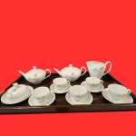 PORCELANA RENNER - Conjunto em porcelana branca da renomada marca Renner, ricamente decorado com frisos em ouro e delicadas flores em policromia vibrante. Conjunto composto por cinco xícaras com seus respectivos pires, dois bules, café e chá, uma leiteira, e uma manteigueira. Obs, não acompanha bandeja de servir da foto.