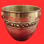 Cachepot estilo art deco, século XX, em metal espessurado a prata, decorado por flores em relevo, com duas pegas laterais em formato circular. Medida: 20cm x 22cm.