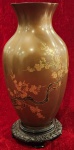 Antigo Vaso Oriental, inicio do século XX, confeccionado em peça única em baquelite no tom marrom, decorado no tom dourado em misto de flores de cerejeira, acompanha penha  ricamente ornamentada no tom preto. Medida: 30cm.