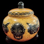 DB WB - Grandioso recipiente, Alemão, do final do século XIX, cerâmica vitrificada, com tampa e rica decoração em relevo de figuras estilizadas semelhantes a máscaras e pés em esferas, Marca da manufaturada base. Medida: 30cm x 30cm.