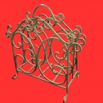 Antigo revisteiro, anos 60, confeccionado em ferro fundido, com design de arabesco com volutas vazadas e pés curvos. Medida: 45cm x 45cm.