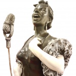 Magnifica Escultura Italiana " CANTORA" década de 1940,  representando figura feminina com um microfone estilo vintage e um xale de plumas. Confeccionada em resina pintada e patinada no tom preto. medida: 77cm.