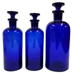 COLECIONISMO - Conjunto contendo três potes de farmácia antigos, art deco anos 50, confeccionado em vidro no tom azul cobalto, peça utilizada para armazenar medicamentos ou substâncias homeopáticas. Medida: 22cm e 19cm.