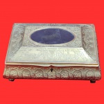 Caixa no estilo francês do século XIX, em metal dourado, decoração ricamente cinzelada com guirlandas e flores em relevo, sustentado por quatro pés em forma de bola. Medida: 22cm x 15cm x 8cm.
