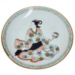 "Medalhão", antigo prato decorativo, porcelana esmaltada período Meiji XX,  com rica decoração policromada por cena central de uma gueixa e adornado com bordas douradas e detalhes folhados. Medida: 30cm.
