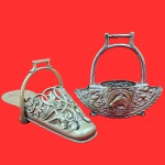 Par de estribo em bronze patinado, com ricos trabalhos detalhados em relevo, incluindo motivos florais e figura de uma ferradura com uma cabeça de cavalo. Medida maior: 28cm x 11cm.