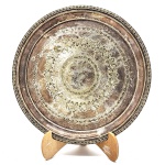 Antiga bandeja em metal espessurado a prata, com rica decoração no padrão de arabescos em relevos, bordas decorada em relevos. Medida: 30cm. obs no estado.