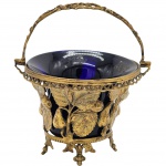 Antiga e delicada cesta, estilo art nouveau em metal no tom ouro velho, decorado em galeria vazada no padrão de frutas e folhas. Acompanha Bowl interno no tom azul cobalto. Medida:  17cm x 15cm.