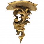 Peanha antiga de madeira, típica do estilo barroco ou rococó, com entalhes detalhados e acabamento dourado, frequentemente usada como suporte decorativo para imagens sacras ou objetos de arte. Medida: 20cm x 17cm.