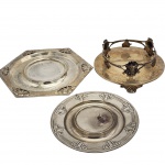 Três porta garrafa, com ricas decorações em relevos, sendo no estilo art nouveau, anos 50, peças em metal espessurado a prata. Medida maior: 25cm.