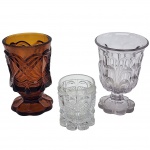 Conjunto de três peças decorativas, no estilo Art Déco, apresentando padrões geométricos em relevo e base em pedestal de bordas onduladas. Peça transparente em cristal Bacarat. Medida da peça maior: 13 cm x 8 cm.