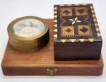 Conjunto, contendo três caixas, sendo uma caixa para baralho em madeira marchetada, uma caixa com fechamento em metal dourado e uma caixa em metal decorada com busto feminino. Medidas: maior 22 cm x 18 cm; menor 10 cm x 4 cm.