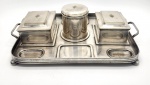 Suporte de Mesa, estilo Art Deco, dois compartimentos para canetas em formato retangular, fundo madeira, um tinteiro com tampa e um suporte central, confeccionados em metal espessurado a prata . Medida badeija: 45cm x 30cm.