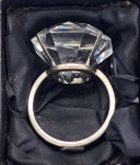 Porta guardanapo, em formato de anel de formatura. Em metal espessurado a prata e pedra ao feitio de diamante. Medida: 7cm x 5cm.
