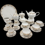 PORCELANA MAUA - Parte de conjunto composto por dois bules, um açucareiro, uma manteigueira, uma leiteira, um prato raso, cinco xícaras com seus pires e cinco xícaras de chá com seus pires. Decorado em padrão floral com frisos dourados.