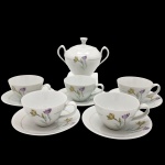 RENNER - Parte de conjunto em porcelana branca vitrificada, composto por cinco xícaras com seus pires e um açucareiro. Rica decoração policromada em padrão floral. Observação: uma xícara e a queijeira apresentam fio de cabelo.
