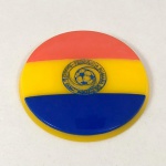 FUTEBOL DE BOTÃO (08) - BOTÃO da SELEÇÃO da ROMÊNIA em acrílico, com as cores azul, vermelha e amarela, com o escudo do time ao centro. Botão com duas camadas. Mede aprox. 40 mm na superfície inferior.