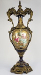 SEVRES  PALACIANA ÂNFORA EM PORCELANA DE SEVRES DE MUITO GRANDE DIMENSÃO. FORMIDÁVEL GUARNIÇÃO EM BRONZE ORMOLU. REQUINTADAS ALÇAS LATERAIS QUE LE ELEVAM ENRUBESTECENDO AINDA MAIS A PEÇA.  INUSITADA DECORAÇÃO COM CENA DE PERSONAGENS VESTIDOS Á MANEIRA DO SEC. XVIII. JUNTO A UMA FONTE COM FEITIO DE DOPHIN DE CUJA BOCA JORRA A ÁGUA UM CAVALHEIRO SE RECOSTA EM GALANTEIO A UMA BELA DAMA QUE ESTÁ LAVANDO SUAS MÃOS NA ÁGUA DA FONTE. O CASAL É SURPREENDIDO PELA MÃE DA DAMA QUE APONTA O RUMO DA CASA PARA A DONZELA COMO QUE EXORTANDO-A AO RECATO DOMÉSTICO. NA FACE OPOSTA UMA PAISAGEM COM MANSÃO JUNTO A UM LAGO. O BRONZE É DE ESPETACULAR QUALIDADE ASSIM COMO A PINTURA E A RICA DOURAÇÃO. MARCAS DA MANUFATURA DE SEVRES SOB A BASE. FRANÇA, SEC. XIX. 83 CM DE ALTURA. Há um fio de cabelo na região da reserva com a cena da mansão junto ao lago. Também um restauro profissional foi realizado junto à base.