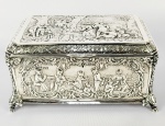 HANAU  MARCAS DO PRATEIRO FRIEDRICH REUSSWIG  PERÍODO VITORIANO. FORMIDÁVEL CAIXA COFRE EM PRATA DE LEI COM MARCAS DE HANNAU PRATEIRO FRIEDRICH REUSSWIG E MARCAS DE EXPORTAÇÃO PARA INGLATERRA, CIDADE DE CHESTER, ANO 1870. ESSA LINDA CAIXA TEM EXUBERANTE DECORAÇÃO REPRESENTANDO CENAS DE UM DIA DE FESTEJO. TODAS AS FACES SÃO DECORADAS: EM UMA DELAS UM PIQUINIQUE COMUNAL MUITAS PESSOAS SENTADAS COMENDO E BEBENDO COM UMA CRIANÇA CORRENDO COM OS BRAÇOS ABERTOS EM DIREÇÃO AO PAI QUE SEGURA ESCONDIDA ATRÁS DE SI UMA BONECA PARA PRESENTEA-LA. OUTRA FACE REPRESENTA UMA DANÇA COM UM MÚSICO TOCANDO GAITA DE FOLES. A TAMPA TEM RESERVA COM JOGO DE BOLICHE COM NOVE PINOS NA GRAMA UM JOGO MUITO POPULAR NA INGLATERRA PRINCIPALMENTE NA ERA DA DINASTIA PLANTAGENETA. ERA UM JOGO COM NOVE PINOS E O OBJETIVO PRINCIPAL ERA LANÇAR A BOLA DE FORMA QUE ELA FICASSE O MAIS PERTO POSSÍVEL DOS PINOS SEM DERRUBA-LO. TAMANHA ERA A POPULARIDADE DESSE JOGO QUE O REI EDUARDO III NO SEC. XIV TEMENDO QUE O BOLICHE COM NOVE PINOS SUPLANTASSE A POPULARIDADE DOS JOGOS DE ARCO E FLECHA  (UM ESPORTE COM MAIOR IMPORTÂNCIA MILITAR) BAIXOU UM DECRETO PARA A PROIBIÇÃO DO JOGO DE NOVE PINOS O QUE OBRIGOU OS INGLESES A REINVENTAR O ESPORTE COM DEZ PINOS QUE NÃO ERA TIPIFICADO NA LEI. A PARTIR DAÍ OS DEZ PINOS TORNARAM-SE POPULARES E DERAM ORIGEM AO JOGO DE BOLICHE COMO CONHECEMOS HOJE. AS PEÇAS DE HANAU ERAM OBJETO DE COLEÇÃO DA REALEZA E NOBREZA EUROPÉIA, ATÉ MESMO A IMPERATRIZ AMÉLIA DO BRASIL POSSUIU PEÇAS DE HANAU COMO ENUNCIA O SEU TESTAMENTO COM A DESCRIÇÃO DAS JÓAIS QUE POSSUIA. ALEMANHA, SEC. XIX. 22 X 15 X 11 CM 1020GNOTA: NA indústria de prata antiga de Hanau se especializou em excelentes cópias do trabalho dos antigos ourives, em particular peças de Nuremberg, copos duplos, taças velhas, taças velhas, caixas de rapé e assim por diante. Essas cópias foram marcadas com marcas de fantasia, um pouco parecidas com marcas antigas, que também se harmonizaram com o estilo da peça. Por exemplo, reproduções em estilo rococó francês são marcadas com marcas francesas, peças inspiradas na Alemanha do século XVII têm marcas alemãs e assim por diante. Essas marcas eram geralmente em um estilo remanescente das marcas dos fabricantes dos séculos XVII e XVIII.