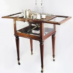 REQUINTADO BAR POP-UP EM MOGNO ESTILO E ÉPOCA EDWARDIANA. DOTADO DE RODÍSIOS. FORMADO POR UMA CAIXA COM LINDOS VIDROS BISOTADOS NAS LATERAIS E NA PARTE SUPERIOR. AS PORTAS SUPERIORES DUPLAS QUANDO ABERTAS ELEVAM O TABULEIRO COM UM SERVIÇO COM DOIS DECANTERES EM CRISTAL, DOZE CÁLICES EM CRISTAL, 12 PETISQUEIRAS INDIVIDUAIS EM METAL PRATEADO, 1 CIGARREIRA EM CRISTAL, 12 XÍCARAS DE CAFÉ EM PORCELANA E  CREMEIRA COM AÇUCAREIRO E CAFETEIRA EM METAL PRATEADO. TODAS AS PEÇAS IMPECÁVEIS. ESTE BELO BAR POP-UP É UMA PEÇA DE GABINETE MASCULINO, OU FUMIER ONDE OS CAVALHEIROS SE REUNIAM APÓS OS JANTARES PARA CONVERSAR ENQUANTO AS DAMAS ACOMPANHAVAM A ANFITRIÃ ATÉ A SALA DE CHÁ ONDE CONVERSAVAM OS ASSUNTOS FEMININOS E AMENIDADES SOCIAIS. LUXUOSO, IMPECÁVEL E MAGNÍFICO! INGLATERRA, INICIO DO SEC. XX. 77 X 48 X 40 CMNOTA: No período Vitoriano, no final do sec. XIX e no período Eduardiano no início do XX, as  refeições eram geralmente compostas por 10 pratos e sobremesa. Durante a refeição, os homens precisavam sempre conversar com as mulheres que sentavam à sua direita. Após o jantar, as mulheres seguiam para uma sala onde bebiam chá e conversavam. Os homens iam para outra sala, onde fumavam e conversavam também. Nesse espaço informal além de fumar, bebiam, conversavam e jogavam.