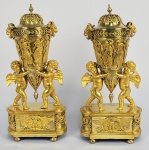 RUSSIA IMPERIAL   ESCOLA DE  FRIEDRICH BERGENFELDT (1760-1822). MAGNÍFICO PAR DE ANFÔRAS EM BRONZE DOURADO COM REPRESENTAÇÃO RELEVADA DAS HORAS. PEGAS LATERAIS COM FEITIO DE CABEÇAS DE LEÕES COM CHIFRES DE CARNEIRO. OS VASOS SÃO SUSTENTADOS POR DOIS QUERUBINS QUE SE COLOCAM SOBRE UMA BASE DECORADA COM UMA ÁGUIA E GUIRLANDAS. UM PAR IDENTICO A ESTE INTEGRA O ACERVO DO PALACIO DE PAVLOSK EM SÃO PETESBURGO. O BRONZIER NASCIDO NA ALEMANHA FRIEDRICH BERGENFELDT ESTAVA TRABALHOU EM SÃO PETERSBURGO DURANTE A DÉCADA DE 1790, APÓS O QUE VOLTOU A  TRABALHAR EM PARIS. MAS EM 1801 ESTAVA MAIS UMA VEZ NA RÚSSIA E PROVOU SER MUITO PRODUTIVO DURANTE A PRIMEIRA DÉCADA DO SÉCULO XIX. ELE FOI SEM DÚVIDA UM DOS MELHORES BRONZEADORES QUE TRABALHOU EM SÃO PETERSBURGO DURANTE ESSE PERÍODO E, COMO SEUS CONTEMPORÂNEOS, COMO BAUMANN OU JP LANCRY, FORNECEU VÁRIOS BRONZES PARA  À CORTE E À ARISTOCRACIA IMPERIAL RUSSA. ELE COLABOROU REGULARMENTE COM O ÉBÉNISTE HEINRICH GAMBS, PARA QUEM FORNECEU ELABORADOS FLOREIROS EM BRONZE. EMBORA ELE GERALMENTE TRABALHASSE COM DESENHOS DE OUTROS, SEUS BRONZES MOSTRARAM UMA SEMELHANÇA DISTINTA COM O TRABALHO DO BRONZEADOR PARISIENSE CLAUDE GALLE. FOI O INFLUENCIADOR DE TODA UMA GERAÇÃO DE ARTESÃOS EM BRONZE RUSSOS. RÚSSIA, SEC. XIX. 34 CM DE ALTURA NOTA: As Horas (constituíam, na mitologia grega, um grupo de deusas que presidiam sobre as estações do ano. Filhas de Zeus e Têmis, elas personificavam a ordem do mundo e originalmente eram as porteiras do monte Olimpo. Eram também guardiãs da ordem natural, do ciclo anual de crescimento da vegetação e das estações climáticas anuais