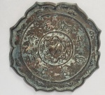 DINASTIA SONG (960-1279)  BELISSIMO ESPELHO EM BRONZE DECORADO EM RELEVO. MEDALHÃO CENTRAL TEM PASSADEIRA PARA FIO DE SUSTENTAÇÃO. CARACTERES RELEVADOS E ANÉIS CONCÊNCTRICOS DECORAM A PEÇA. LINDO FEITIO RECORTADO. CHINA , DINASTIA SONG (960-1279), 18 CM DE DIAMETRONOTA: Os espelhos de bronze têm uma longa história na cultura chinesa, datando pelo menos do século 11 Antes da Era Comum (DC). Muitos espelhos foram colocados com seus donos em túmulos antigos. Alguns foram transmitidos de geração em geração por muitos anos na mesma família.Os espelhos eram mais uniformes e tipicamente redondos na Dinastia Han (206 aC  220 dC), enquanto uma maior variedade é observada nas dinastias Song e Yuan (séculos 10 a 14), quando formas diferentes, como oblongas e octogonais, apareceram. Alguns espelhos têm uma alça ou ilhós para pendurar. Nos últimos séculos, durante o reinado da dinastia Qing (1616-1911), os espelhos de bronze foram gradualmente substituídos por espelhos de vidro.Os espelhos eram usados na China antiga da mesma forma que são usados hoje - as pessoas olham para si mesmas. Mas o espelho também era um objeto de arte e freqüentemente incluía significados e funções cosmológicas, espirituais e até mágicas.A frente do espelho é tão finamente polida que pode refletir a imagem do rosto do usuário. O espelho geralmente é redondo, conectando um conceito de forma ideal com a teoria cosmológica chinesa de 'cúpula hemisférica'. A parte de trás é frequentemente decorada com um botão e vários motivos, como fênix, animais, flores, folhas e treliças. Alguns também têm inscrições. As mudanças de estilo e decoração entre diferentes períodos históricos refletem a evolução de ideias e preferências sociais e culturais. A variedade estilística ajuda colecionadores e historiadores a classificar os espelhos e inferir sua antiguidade.A maioria dos espelhos de bronze são redondos  uma forma que simboliza perfeição e bem-aventurança. Formas redondas na China antiga também representavam reunião, fortuna e amor e casamento satisfatórios. Como a natureza do reflexo é um tanto misteriosa, as pessoas tendiam a associar os espelhos ao sobrenatural. Eles poderiam, acreditava-se, dissipar os males e, portanto, os espelhos se tornaram um acessório funerário favorito. Também deviam manter o lar a salvo do mal, dos criminosos e do infortúnio. Os antigos chineses usavam espelhos em várias funções sociais. Eles foram dados como presentes para e por imperadores e pessoas comuns. Nos rituais budistas e taoístas, os espelhos de bronze eram uma importante parafernália de adoração. Com sua propriedade de refletir a luz, o espelho era um acessório adequado para Buda  Luz Eterna.