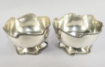 PAR DE LINDOS CACHEPOS EM PRATA DE LEI TEOR 833. BORDA RECORTADA FINALIZADA COM PEROLADOS. A BASE SEGUE A MESMA FÓRMULA DECORATIVA. BRASIL, SEC. XX. 15 CM DE DIAMETRO. 615 G