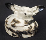 THEODORE HAVILAND -  LINDA CAIXA EM PORCELANA COM FEITIO DE RAPOSA. FRANÇA, INICIO DO SEC. XX. 14 CM DE DIAMETRONOTA: No princípio do sec. XX, com a criação da Sociedade Hípica Paulista pelo  Conde Eduardo Prates, seu sócio numero 1 e por seu filho Guilherme Prates institui-se o costume de torneios de caça a raposa à inglesa, na cidade de São Paulo.  O interessante documentário CAÇA Á RAPOSA produzido pela Campos Filmes (Antônio Campos) em 1913 registra a competição de caça a raposa oficializada pelos sócios da hípica nesse ano. No documentário cerca de quarenta cavaleiros paramentados com roupas de equitação, buzinas e cartolas, são mostrados em cortejo nos jardins da mansão do CONDE EDUARDO PRATES passando pelos portões da mansão e se dirigindo a região chamada barro branco. Não era uma caçada propriamente à raposa, uma vez que o nobre hábito bretão por falta de raposas em nossa fauna local, era  mimetizado pela elite paulista apresentando como alvo da caça, um cavaleiro habilidoso que partia na frente de todos com objetivo de perseguição, era um cavaleiro raposa. Na Santa Gertrudes também eram organizadas caças a raposa nesses moldes, assim como partidas de polo e concursos de salto com obstáculo. Corridas de cavalos e corridas com trolleys.