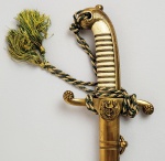 TRANSIÇÃO IMPÉRIO REPÚBLICA (SABRE CONVERTIDO) - RARO SABRE DE OFICIAL  DO CORPO DE SAÚDE DO EXÉRCITO COM PASSADOR E BAINHA EM COURO E METAL  MARCAS DO IMPORTADOR CUNHA GUIMARÃES & Cª SIRGUEIROS E FABRICANTES DE UNIFORMES MILITARES RUA DA QUITANDA 68  CASA FUNDADA EM 1823 NA CORTE DO RIO DE JANEIRO. PUNHO COM POMO E GUARDA MÃO EM BRONZE. PEGA EM MARFIM. NO GUARDA MÃO RESERVA COM SERPENTE ENROLADA EM CADUCEU ENTRE RAMOS DE FUMO E DE CAFÉ. LÂMINA COM RICO ADAMASCADO COM ARMAS DA REPÚBLICA, ELEMENTOS MILITARES COMO ESCUDOS, ESPADAS CRUZADAS, LANÇAS ENTRELAÇADAS POR LAURÉIS. MARCAS  DO FABRICANTE DE LAMINAS DE SOLINGEM CARL REINHARDT KIRCHBAUM (UM ELMO SOBRE ARMADURA). O MODELO DE ESPADA DE OFICIAL-GENERAL ATUALMENTE EM USO FOI ADOTADO EM 1831. É A ARMA REGULAMENTAR DE MAIS LONGO USO NA HISTÓRIA MILITAR DO BRASIL. SOFREU PEQUENAS MODIFICAÇÕES AO LONGO DO TEMPO, SENDO AS MAIS NOTÁVEIS A SUBSTITUIÇÃO DO BRASÃO IMPERIAL GRAVADO NA LÂMINA PELAS ARMAS DA REPÚBLICA APÓS A PROCLAMAÇÃO, EM 15 DE NOVEMBRO DE 1889. BRASIL, DEC. 1890. 80 CM DE COMPRIMENTO. NOTA: A organização autônoma e independente do corpo de saúde do Exército foi regulamentada pelo decreto nº 601, de 19 de abril de 1849, marco importante na história, pois, pela primeira vez, foram regulamentados os cargos com suas atribuições. Antes deste decreto, o serviço de saúde era unificado das forças armadas, que na época eram o Exército e a Real Armada (Marinha do Brasil). Em 1851, foi regulamentado o concurso para médico do Exército Brasileiro: eram admitidos para vaga de segundo cirurgião aqueles que obtivessem grau de doutor e no mínimo três anos de experiência. Em 1857, foram criados os cargos de enfermeiros e farmacêuticos, assim como, as farmácias e o Laboratório Químico Farmacêutico Militar, que tem por função criar compostos químicos e farmacêuticos e fornecê-los aos estabelecimentos militares em geral. Esse foi um período importante para a estruturação do corpo de saúde do Exército, no entanto, ocorreram mudanças neste ano de 1857, onde se extinguiu o concurso para admissão de médicos e farmacêutico e a direção dos hospitais militares foi entregue aos oficiais combatentes, militares não pertencentes ao serviço de saúde. Essa estruturação permitiu que no conflito do Paraguai os profissionais do corpo de saúde do exercito atuassem com louvor no atendimento dos feridos nos fronts de batalha.