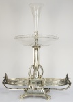 WMF - FAUSTOSO CENTRO DE MESA/EPERGNE EM METAL ESPESSURADO A PRATA. EM MAGNIFICO ESTADO DE CONSERVAÇÃO COM TODOS OS CRISTAIS ORIGINAIS E INTEGROS. NAS DUAS EXTREMIDADES ÁGUIAS COM ASAS ABERTAS. LAURÉIS NO FUSTE. NO ÁPICE UMA FLOREIRA COM FEITIO DE CORNETA TAMBÉM EM CRISTAL. MARAVILHOSA! ALEMANHA, INICIO DO SEC. XX. 85 X 67 CM