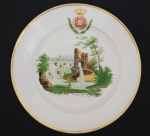 SERVIÇO DO REINO UNIDO DE PORTUGAL, BRASIL E ALGARVES  ESSE MESMO PRATO AGOR EM LEILÃO  FOI O ESCOLHIDO POR JENNY DREIFFUS PARA ILUSTRAR O SERVIÇO DO REINO UNIDO NA PAGINA 178 DO LIVRO LOUÇA DA ARISTOCRACIA NO BRASIL. PRATO EM PORCELANA DECORADO COM BRASÃO DE ARMAS DO REINO UNIDO DE PORTUGAL, BRASIL E ALGARVES NA ABA. O BRASÃO É APRESENTADO ENTRE LAURÉIS QUE SERIAM PRECURSORES DO FUTURO BRASÃO DE ARMAS DO PRINCIPE DO BRASIL DOM PEDRO I E MAIS TARDE ADOTADOS NO BRASÃO DE ARMAS DO BRASIL IMPERIAL. NA CALDEIRA MAGNIFICA RESERVA COM CASCATA E RUÍNAS. O APARELHO FOI ENCOMENDADO POR DOM JOÃO VI PARA COMEMORAR A ELEVAÇÃO DO BRASIL A REINO UINIDO A PORTUGAL E ALGARVES EM 16 DE JANEIRO DE 1815, TALVEZ SE IMAGINASSE QUE EM SETE ANOS O BRASIL REIVINDICARIA SUA POSIÇÃO COMO PAÍS INDEPENDENTE DE PORTUGAL O REI NÃO TERIA FEITO TAL ENCOMENDA, NEM SE AGRADARIA EM FAZER USO DELES EM SUA MESA, A ELEVAÇÃO DO BRASIL FOI O PRIMEIRO PASSO PARA ASPIRARMOS A INDEPENDÊNCIA. O ANUARIO DO MUSEU IMPERIAL DE PETRÓPOLIS REVELA TRATAR-SE ESSE APARELHO DO MAIS SOLENE NA CORTE DE DOM JOÃO VI E INFORMA SER MANUFATURA DA FÁBRICA DE PORCELANA DUC DE ANGOULEME DE PASTA DURA FUNDADA EM 25 DE FEVEREIRO DE 1781 NA RUE DE BONDY, PARIS, POR CHRISTOPHE DIHL, UM ESPECIALISTA EM COR E MODELADOR DE NACIONALIDADE ALEMÃO (1752-1830), ANTOINE GUÉRHARD (D.1793) E SUA ESPOSA LOUISE-FRANÇOISE-MADELEINE CROIZÉ (1751-1831). ESSA ATRIBUIÇÃO DA FABRICAÇÃO SE DEU GRAÇAS A DESCOBERTA DE UM PRATO QUE TRAZIA A MARCA DA FÁBRICA DE ANGOULËME. NO PERÍODO DESSA ENCOMENDA (DÉCADA DE 1810) A AQUISIÇÃO DA LOUÇA DA MONARQUIA EUROPÉIA MUDOU DE PERFIL. JÁ HÁ ALGUNS ANOS A FÓRMULA PARA PRODUZIR PORCELANA, UTILIZADA PELOS CHINESES HÁ SÉCULOS, FOI REVELADA GRAÇAS AOS ESFORÇOS DE INVESTIMENTO DO REI AUGUSTO II , DA BAVIERA E DE OUTROS AGENTES QUE ATUARAM EM PESQUISAS PARA DESENVOLVER A PORCELANA EUROPÉIA. AOS POUCOS, AS CASAS REINANTES PASSARAM A OPTAR PELA LOUÇA DO CONTINENTE PRINCIPALMENTE AS PRODUZIDAS NA FRANÇA. OCORRE QUE AS PORCELANAS CHINESAS OSTENTAVAM UM REQUINTE EXÓTICO, COM SÍMBOLOS E DECORAÇÃO ALHEIAS A CULTURA DO ENCOMENDANTE. AS REQUINTADAS LOUÇAS FRANCESAS ATENDIAM EM SUA DECORAÇÃO OS PRINCÍPIOS DE RESGATE OS VALORES NACIONAIS, A SUNTUOSIDADE E A NOBREZA DE SUAS CASAS REINANTES. DONA MARIA I, AINDA LÚCIDA JÁ TERIA ENCOMENDADO LOUÇA A FÁBRICA FRANCESA DE DUC DE ANGOULAINE. MAS CERTAMENTE FOI DOM JOÃO VI A ADERIR COM MAIOR DEVOÇÃO AO LUXO DA PRODUÇÃO DA PORCELANA FRANCESA E ALEMÃ.. DIZ O ANUÁRIO DO MUSEU IMPERIAL EDITADO EM 1942 A RESPEITO DAS LOUÇAS BRAGANTINAS: Quase no fim os preciosos aparelhos da China, com raras peças que ainda teimavam em ostentar a sua estranha suntuosidade, d. Maria I, ainda lúcida, nas calmas de sua corte respeitosa, fez para a França as grandes encomendas da fábrica nobilíssima do Duc dAngoulême, que deram a d. João infinito prazer. Entre essas as que contavam delicados pratos com o entrecho pitoresco das fábulas de La Fontaine. Ao lado desses não ficavam em posição inferior outros serviços usados no Brasil pela real casa lusitana. Foram muitos. Das mais soberbas e preconizadas marcas. Sèvres, Saxe, Bourg-la-Reine, Chantilly, Sarreguemines, Capo di Monte, o vieux Limoges. Todos esses aparelhos, os mais caros e apreciados da época (não se serviam com mais fausto os grão-senhores das cortes européias) eram apenas complemento às referidas peças de porcelana francesa de fabrico do Duc dAngoulême, que apresentam na borda a coroa do Reino Unido e ao centro uma paisagem, ou simplesmente o escudo real (serviço do Reino Unido) . Esses que passaram mais tarde das mãos reais à tradição da família brasileira, especialmente daquelas castas mais achegadas ao paço, das saudosas matronas patrícias que foram amigas íntimas da princesa Isabel e d. Teresa Cristina, e no leilão do Paço Imperial atropelavam o paciente Virgílio com um chorado peditório de um sapato velho, que a medo escondiam no seio, um lenço usado, um grampo de chapéu, uma negalha de cabelo ainda agarrado à tartaruga dos pentes, qualquer coisinha, um pequeno nada que tivesse pertencido à mãe dos brasileiros, Dona Thereza Cristina . Não só as pessoas fidalgas, que possuíam brasões de armas registrados em cartórios de nobreza e desenhados pelo lápis acatado de Luiz Aleixo Boulanger. Muita gente humilde. Muito fiel servidor do paço ou descendente da abundante famulagem de Petrópolis, de Santa Cruz e da Boa Vista. Conheço o filho de um antigo cocheiro da quinta que ainda guarda uns pratos imperiais, com emblemas e frisos de ouro, e não os larga por dinheiro nenhum, nem à mão de Deus Padre. Infelizmente torna-se penoso identificar todo o conjunto restante das louças da monarquia. O catálogo do leilão da Boa Vista é, de parte o seu alto valor documentário, impreciso e deficiente na explanação dos seus dois mil e tantos lotes. Há muita dúvida na sua descrição, na qualidade, marca, cor, desenho e procedência dos seus múltiplos componentes. Existia no Paço da Cidade, como nas outras moradias reais, muita louça sem brasão, iniciais ou siglas de fabrico, principalmente na fazenda de Santa Cruz, cujos armários resplendiam com mais de vinte serviços da ilustríssima Companhia das Índias. Com o inevitável rumo dispersivo causado pelo leilão, muita coisa desapareceu, mergulhou no tumulto dos acontecimentos, sem que pudesse ser analisada nos seus menores detalhes, classificada ao menos na sua vaga aparência. Não obstante, foram os lotes dessa inesquecível justa de arte que revelaram a existência de muita porcelana fina que corre a via sacra dos antiquários e leiloeiros, em meio século de República. Sem que ninguém percebesse, pela falta absoluta de provas de identidade, foram por isso adquiridas a preços irrisórios e mesmo depreciadas por amadores displicentes que imaginavam que nas mesas imperiais só poderiam figurar louçarias que se distinguissem por coroas ou monogramas de príncipes. Talloni, pouco antes de falecer, cedeu ao dr. João do Rego Barros, o aprimorado amador de arte antiga que o Rio de ontem conheceu e estimou. Talloni era um jovem oficial, quando se deu o leilão de Santa Cruz. Morava aí ou servia próximo, nos seus lidares de militar brioso. Ainda o conheci, capitão do Exército, no Colégio Militar, à flor dos meus verdes anos. Era um tipo de homem exemplar na sua rígida conduta. Sua palavra, seu conceito sempre portava por fé. De verdadeiro servidor da pátria as suas atitudes, o fiel cumprimento do dever. Assim, tudo que ele pudesse ter declarado ao confiar a Rego Barros as peças imperiais que adquirira vale um documento histórico, por um tributo de serena honestidade. Dentre os espécimes por ele adjudicados, revelam-se aqueles, até então desconhecidos, que hoje refulgem nos mostruários dos museus e exibem finas decorações de flores, animais, paisagens e pássaros. São já bastante conhecidos dos amadores e não deixam a menor dúvida quanto à sua procedência, das suas primorosas pinturas tiravam os serviçais do paço as pitorescas alcunhas. Ao pôr a mesa para os ágapes, eles diziam, pela voz do mordomo: Hoje é a louça dos pastores. Ou, em dia de gala: O rei hoje, data do seu aniversário, vai gostar de comer nos pratos dos pavões. E assim, como um florido calendário, iam essas jóias de valor se entremostrando ao sol de cada dia. Na coleção Andrade Pinto, no museu do Instituto Histórico, existe um raro exemplar da louça dita das casas, de idêntica filiação, que, por opostos caminhos, o infatigável amador pudera classificar como pertencente a serviço de propriedade do príncipe d. João. 1. E muito alegre ficou, quando Carlos Frederico, esse outro arguto e inteligentíssimo maníaco, lhe mostrou alguns exemplares que completavam a série, juntamente com o mais rico, o das fábulas, cuja beleza e raridade, com efeito, não têm rival. As marcas das porcelanas desse período, geralmente conhecidas por Vieux Paris, às vezes sem determinação precisa de local e de época, o que atormenta o colecionador, desapareciam com facilidade. Raríssimas as peças em que ainda hoje se deparam intactas as indicações de ano e de fatura. Eram essas quase sempre gravadas sobre o esmalte a tinta avermelhada-escura; e do serviço de d. João VI, o que tem a coroa na borda do prato, só se conhece, com a marca, o exemplar que se acha no Instituto Histórico. Outros sinais, muita vez convenções, quando não simples iniciais ou algarismos, muito comuns aos obreiros de Sèvres, eram colocados antes do esmaltamento final e gravados na própria porcelana, o que lhes assegura uma impressão indelével. Esse cuidado serve para uma completa identificação dos objetos, no que se refere à mão que os fez e ao tempo que os consagrou. FRANÇA, DEC. 1810. 21,5 CM DE DIAMETRO.